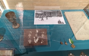 Wnętrze gabloty z pamiątkami Bractwa Kurkowego- posrebrzanym pucharkiem, odznakami oraz fotografiami