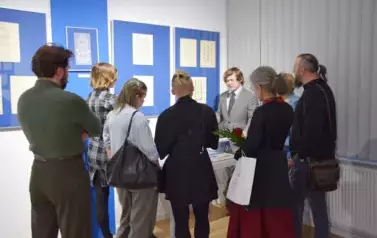 Pracownik muzeum przy gablocie odpowiadajćy na pytania grupy młodzieży
