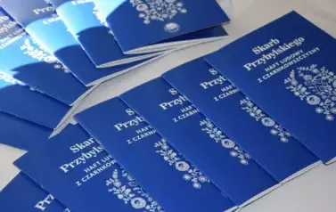 Książki "Skarb Przybylskiego- ludowy haft z czarnkowszczyzny" rozłożone na nakrytym obrusem stoliku